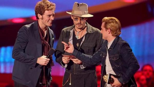 Os atores Sam Claflin (esq) e Josh Hutcherson (dir) recebem prêmio de Melhor Filme das mãos de Johnny Depp (centro). (photo by straitstimes.com)